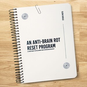 May include: A white spiral-bound notebook with the text "AN ANTI-BRAIN ROT RESET PROGRAM" and "A 3-WEEK RESET FOR RECLAIMING YOUR ATTENTION AND CREATIVITY." The notebook has a silver paper clip and two circular design elements.
