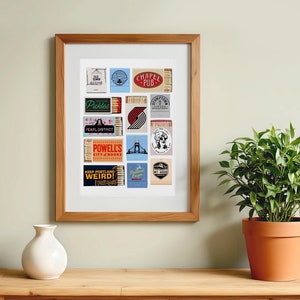May include: A framed print of a collage of matchbox labels featuring various Portland, Oregon landmarks and businesses. The labels include names like "Chapel Pub", "Powell's City of Books", and "Keep Portland Weird!"