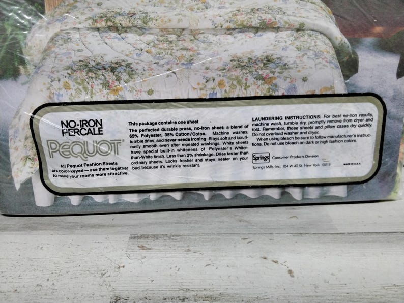 K&ouml;nnte beinhalten: Eine Packung Pequot No-Iron Percale-Bettw&auml;sche. Die Bettw&auml;sche hat ein Blumenmuster mit wei&szlig;en, blauen und gelben Blumen. Die Verpackung enth&auml;lt Text, der die Bettw&auml;sche als eine Mischung aus Polyester und Baumwolle, maschinenwaschbar und knitterarm beschreibt.