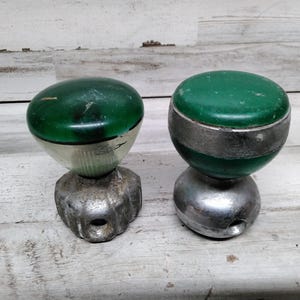 Op de afbeelding: Twee vintage groene en zilveren auto versnellingspookknoppen. De knoppen zijn gemaakt van plastic en metaal en hebben een klassiek ontwerp.