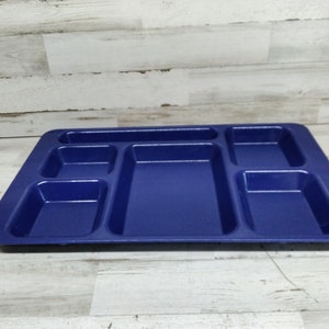 May include: A blue plastic tray with six compartments. The tray is designed for serving food or organising small items.