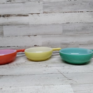 May include: Three vintage Pyrex bowls with handles in orange, yellow, and green.