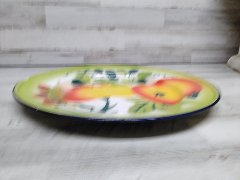 Peut inclure: Un grand plat de service ovale avec un fond vert et un bord bleu. Le plat pr&eacute;sente un motif de fruits color&eacute;s avec des teintes jaunes, orange et rouges.