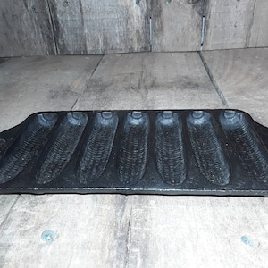 Peut inclure: Un moule à pain de maïs en fonte noire avec six moules individuels. Le moule a une forme légèrement incurvée et une finition noire lisse.