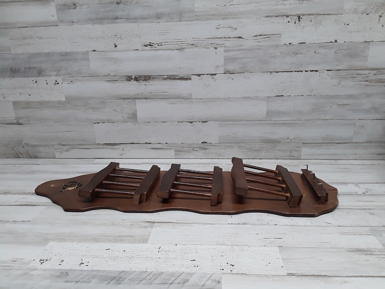 May include: A vintage wooden wall-mounted coat rack with a dark brown finish. The rack features multiple horizontal bars for hanging items. The base is a curved shape with decorative elements.