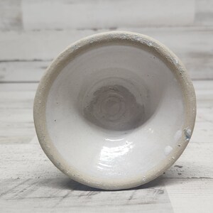 May include: White ceramic bowl with a smooth, glazed interior and a slightly rough, unglazed exterior. The bowl is round and has a wide, shallow shape.