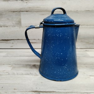 May include: Blue enamel camping coffee pot with a speckled finish and a silver handle.