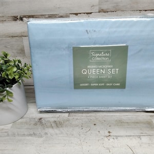 May include: A light blue Queen size sheet set in a clear plastic package. The label reads "Signature Collection" and "Brushed Microfiber Queen Set 4 Piece Sheet Set". The packaging also states "Luxury - Super Soft - Easy Care".