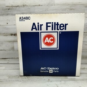 Peut inclure: Une boîte blanche et bleue pour un filtre à air AC Delco. La boîte porte les mots "Air Filter" en grandes lettres bleu foncé. Le logo AC est dans un carré blanc avec un cercle rouge et les lettres "AC". La boîte porte également les mots "AC-Delco Genuine GM Parts".