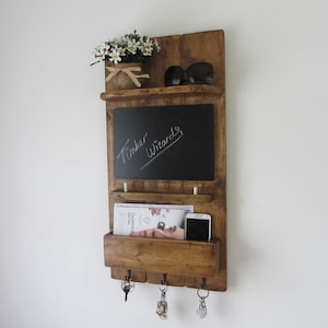 May include: Rustic wooden wall organizer with a chalkboard, a shelf, a mail slot, and key hooks. The chalkboard has the words "Timber Wizards" written on it.