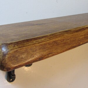 Peut inclure: Une &eacute;tag&egrave;re en bois rustique avec une finition naturelle brune. L'&eacute;tag&egrave;re a un bord l&eacute;g&egrave;rement incurv&eacute; et est soutenue par deux supports m&eacute;talliques.