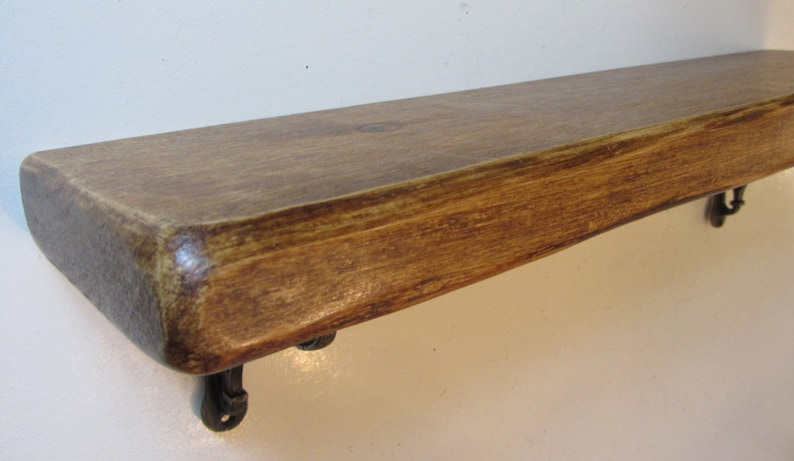 Peut inclure: Une &eacute;tag&egrave;re en bois rustique avec une finition naturelle brune. L'&eacute;tag&egrave;re a un bord l&eacute;g&egrave;rement incurv&eacute; et est soutenue par deux supports m&eacute;talliques.