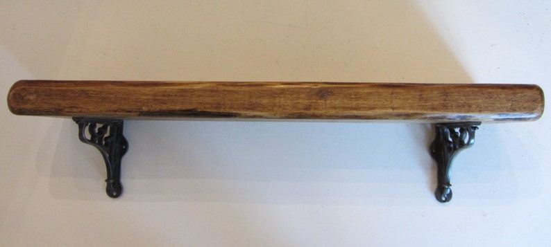 Peut inclure: Une &eacute;tag&egrave;re en bois avec des supports en m&eacute;tal noir. L'&eacute;tag&egrave;re est teint&eacute;e d'une couleur brun fonc&eacute; et a un aspect rustique.