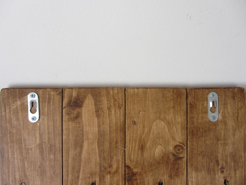 May include: A wooden sign with two metal hanging hooks on the back. The sign is stained a dark brown color.