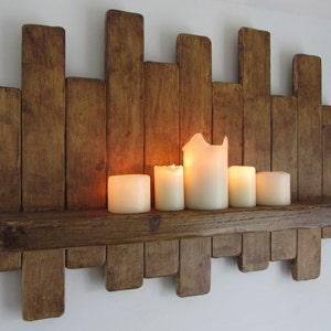 May include: A rustic wooden shelf with a staggered design, featuring a natural wood finish. The shelf has a wide, thick top and is decorated with five lit candles.