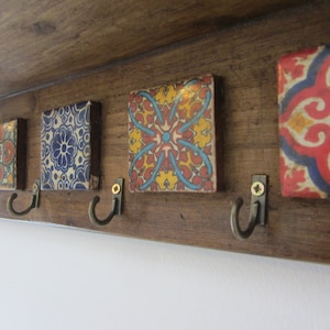 May include: A wooden coat rack with five hooks and colorful tile accents. The tiles feature intricate geometric patterns in shades of blue, red, yellow, and white.