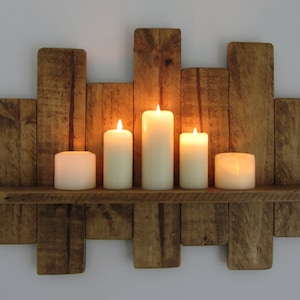 May include: A rustic wooden shelf with a distressed finish, featuring five lit candles. The shelf is made of reclaimed wood and has a unique, handcrafted look.