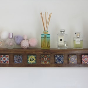 May include: A wooden shelf with decorative tile accents, displaying a variety of perfume bottles and a diffuser with reeds. The shelf is brown with a rustic finish.
