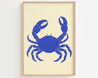 May include: A framed art print featuring a blue crab illustration on a cream-colored background. The crab is depicted with its claws raised, showcasing a detailed design. The artwork is encased in a light wooden frame, suitable for coastal or nautical decor.