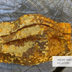 May include: Gold sequined face mask with a nose wire and three layers.  The mask is made of a soft, comfortable fabric and is designed to be reusable.