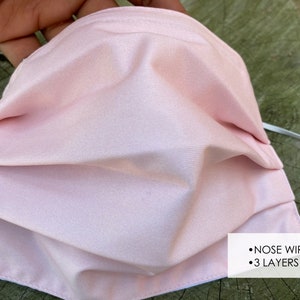 Pu&ograve; includere: Una maschera facciale rosa con un filo per il naso e tre strati. La maschera &egrave; plissettata e ha lacci elastici bianchi per le orecchie.