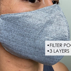 May include: A gray face mask with a filter pocket and three layers. The mask is made of a soft, breathable fabric.