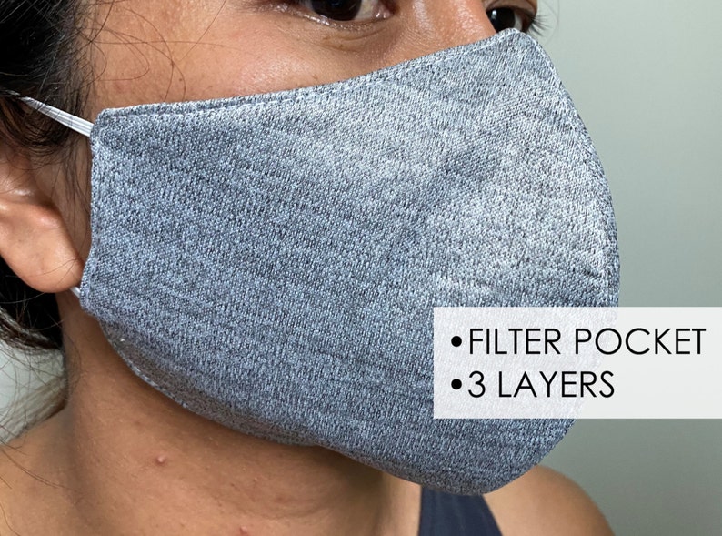 May include: A gray face mask with a filter pocket and three layers. The mask is made of a soft, breathable fabric.