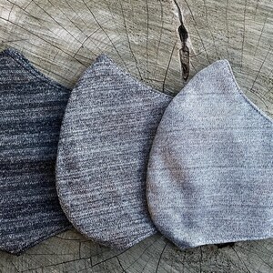 May include: Three face masks made of a soft, textured fabric. The masks are in shades of gray, from dark gray to light gray.
