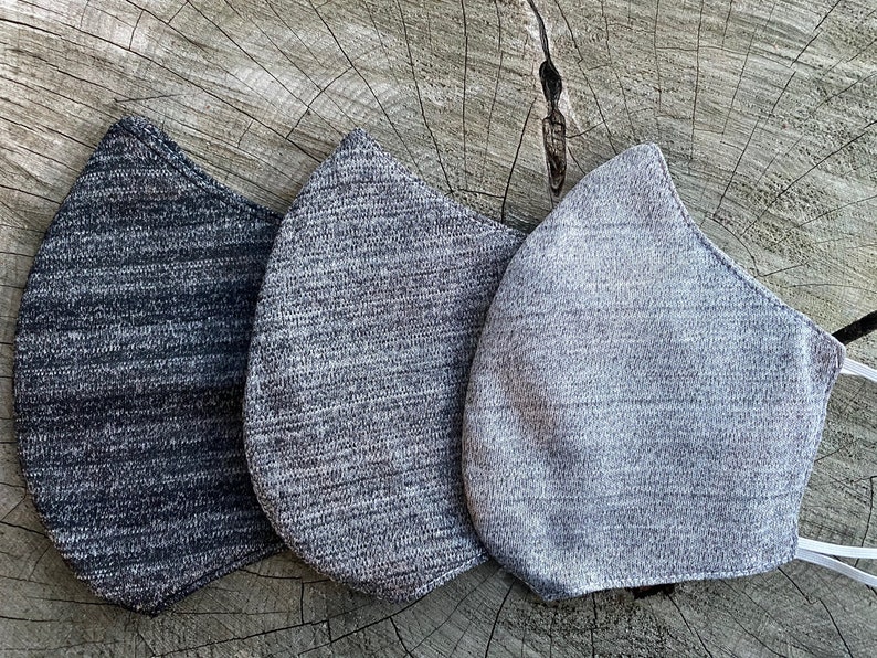 May include: Three face masks made of a soft, textured fabric. The masks are in shades of gray, from dark gray to light gray.