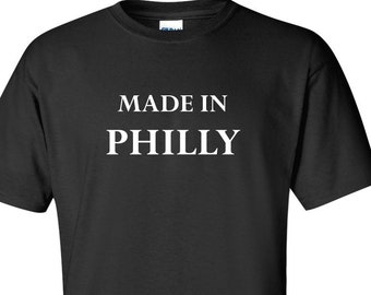 May include: Black t-shirt with the white text "MADE IN PHILLY" printed on the front. The shirt is a short-sleeved crew neck style, suitable for casual wear. The text is centered and in a bold, sans-serif font.