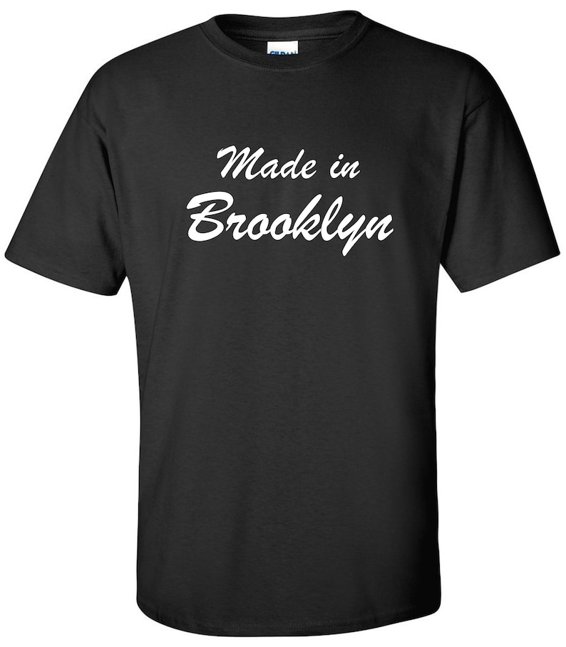 May include: Black t-shirt with white text that reads "Made in Brooklyn" in a cursive font.