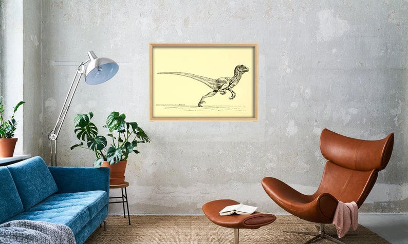 Pu&ograve; includere: Un disegno in bianco e nero di un dinosauro velociraptor che corre, incorniciato in una cornice di legno chiaro contro un muro beige chiaro.
