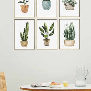 May include: Six framed watercolor prints of potted plants, including a cactus, snake plant, and a variety of leafy plants. The prints are arranged in a grid pattern on a white wall.