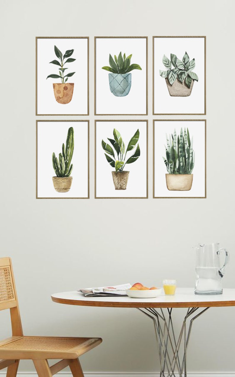 May include: Six framed watercolor prints of potted plants, including a cactus, snake plant, and a variety of leafy plants. The prints are arranged in a grid pattern on a white wall.