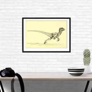 Pu&ograve; includere: Disegno in bianco e nero di un dinosauro che corre, incorniciato in una cornice nera con un passepartout color crema. Lo sfondo &egrave; un muro di mattoni bianchi.