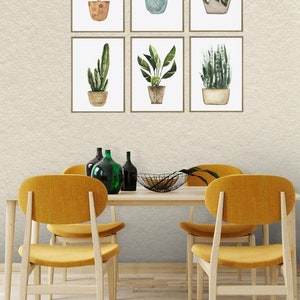 May include: Six framed watercolor illustrations of potted plants, displayed on a wall above a wooden dining table with four yellow chairs.