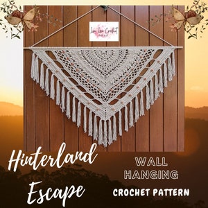 Op de afbeelding: Een gehaakte wandhanger in beige en bruine tinten. De hanger heeft de vorm van een driehoek met franjes langs de onderkant. De tekst "Hinterland Escape" en "Wall Hanging Crochet Pattern" is zichtbaar onderaan de afbeelding.