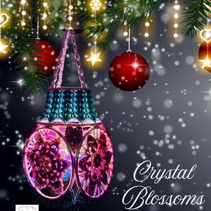 Könnte beinhalten: Eine dekorative Laterne mit einem türkisfarbenen Oberteil und einem rosa-violetten Blumenmuster. Die Laterne hängt an einem Weihnachtsbaumzweig mit roten Ornamenten und sternförmigen Lichtern. Der Text "Crystal Blossoms Lantern" wird angezeigt.