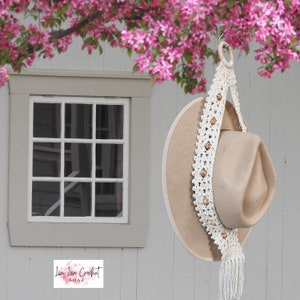 Hat Holster a Beaded Crochet Hat Hanger hanging with a hat in it outside with flowers