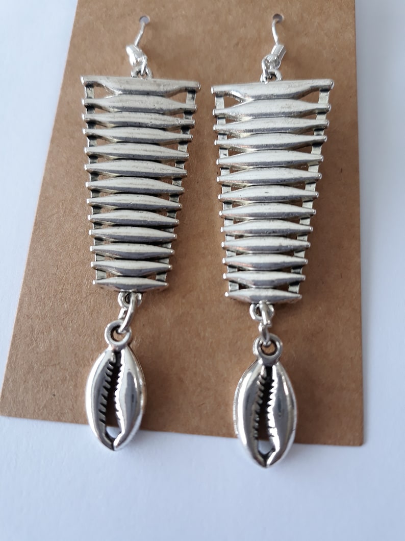 May include: Silver dangle earrings with a geometric design and a shell charm.