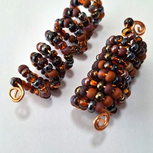 May include: Two brown and black beaded hair coils with copper wire ends.
