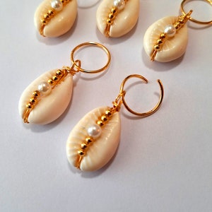 May include: Five gold hair clips with white seashells and pearl accents. Each clip features a small, white seashell with a single pearl bead in the centre, surrounded by gold beads.