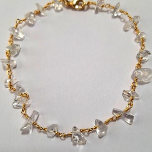 May include: A gold chain bracelet with clear quartz stones. The stones are irregularly shaped and have a natural, raw look.