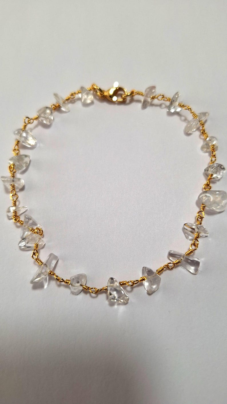 May include: A gold chain bracelet with clear quartz stones. The stones are irregularly shaped and have a natural, raw look.