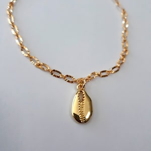 May include: A gold chain bracelet with a gold seashell charm. The chain is a delicate, oval-link style.