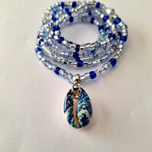 May include: A blue and silver beaded necklace with a blue and white seashell pendant.