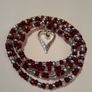 May include: A multi-strand necklace with red and silver beads and a silver heart charm.