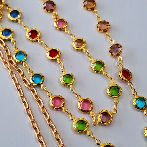 May include: Two gold chains with colorful round glass beads. The beads are in shades of pink, blue, green, and red.