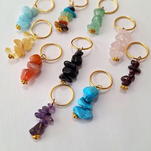 May include: Assorted gemstone keychains with gold-colored rings. The keychains feature various colors, including blue, green, yellow, orange, black, purple, pink, and red. Each gemstone cluster is attached to a small gold-colored metal base.
