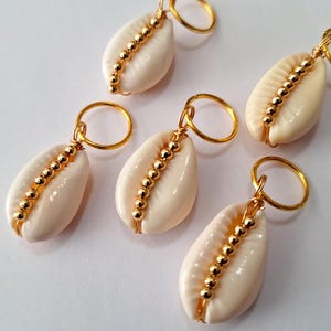 May include: Four gold-toned hair clips with white cowrie shells and gold beads.